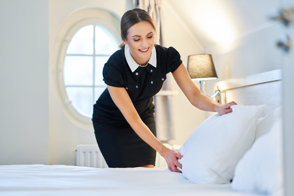 Maid Making Bed in Hotel Room